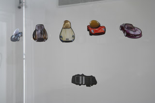 Gijs Bakker display of pins from the series I Don't Wear Jewels, I Drive Them, 2001, colored photos, silver, plexiglass and various precious and semi-precious stones; the pin at bottom is seen from behind.© Gijs Bakker, photo Matthew Suib
