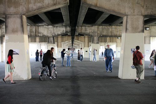 Photo by Chris Pacquette. Scene Under I 95 Sunday, May 4, with people looking at Zoe Strauss's photos installed on the pillars that hold up the highway.