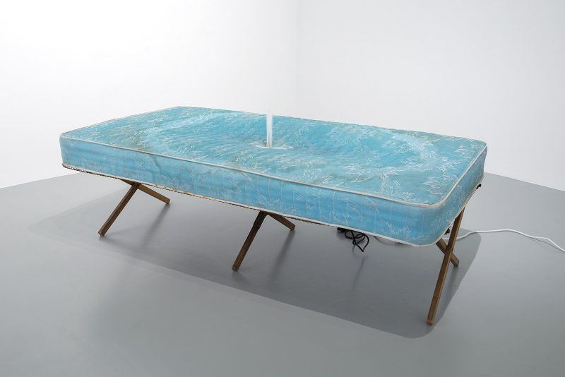 Tristin Lowe, The Bed, 1996, mattress, wood frame, water pump, drain; 25’’x38’’x74. Image courtesy of Rosenwald-Wolf Gallery and Studio LHOOQ. 
