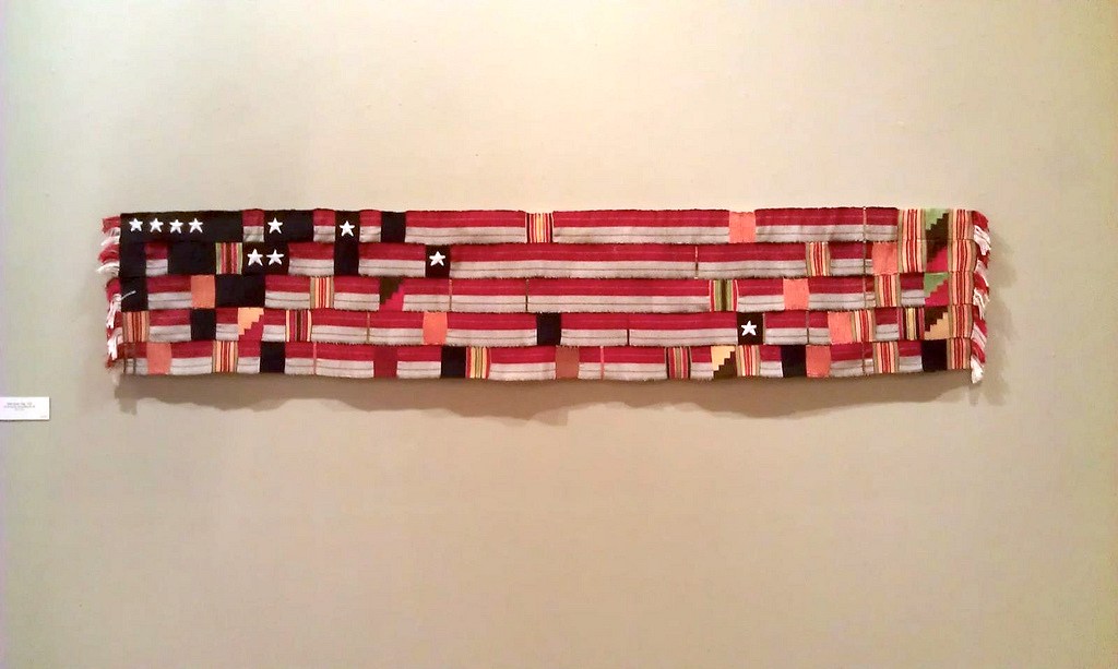 Sonya Clark, Gele Kente Flag, 1995, handwover and embroidered silk and cotton, 15 x 72 inches