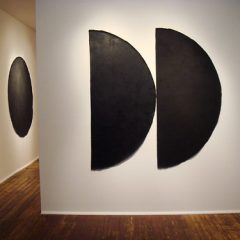 Untitled (October 2005), 2005 Black gesso and acrylic painting mediums on canvas; ca. 72” diameter and through the doorway is Untitled (July 2006), 2006 Black gesso and acrylic painting mediums on canvas; ca. 72” diameter. Photo courtesy of the gallery.