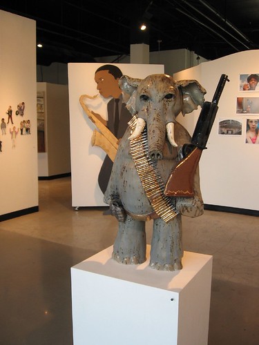 An installation shot of dig, with Nick Lenker's Elephant in the Room, Thom Lessner's John Coltrane behind, small Thom Lessner pieces to left and Zoe Strauss Pushpin Installation of photos to right