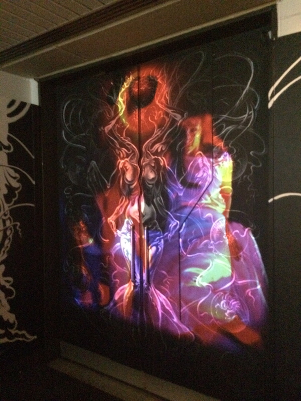 Figures and auras of vivid color are projected into the whimisical wall mural