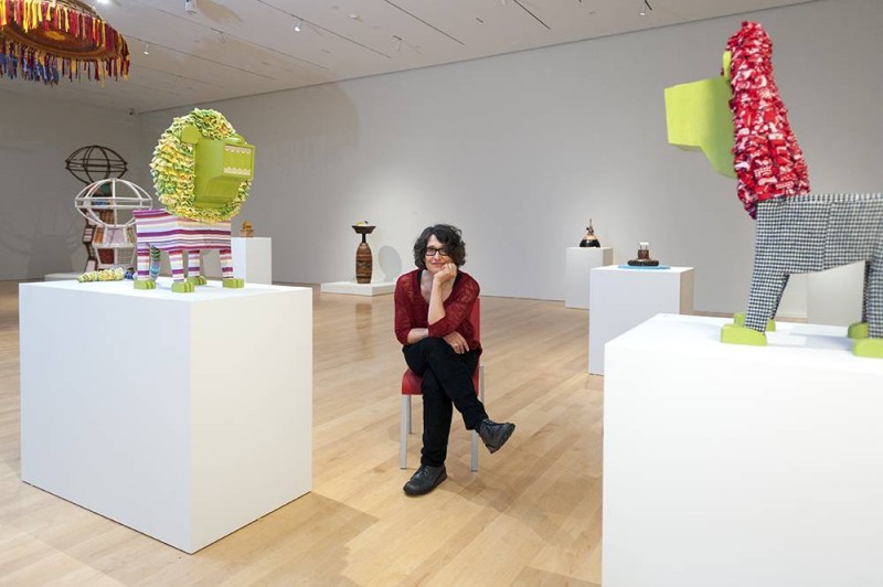 woman sitting in the midst of a sculpture exhibit