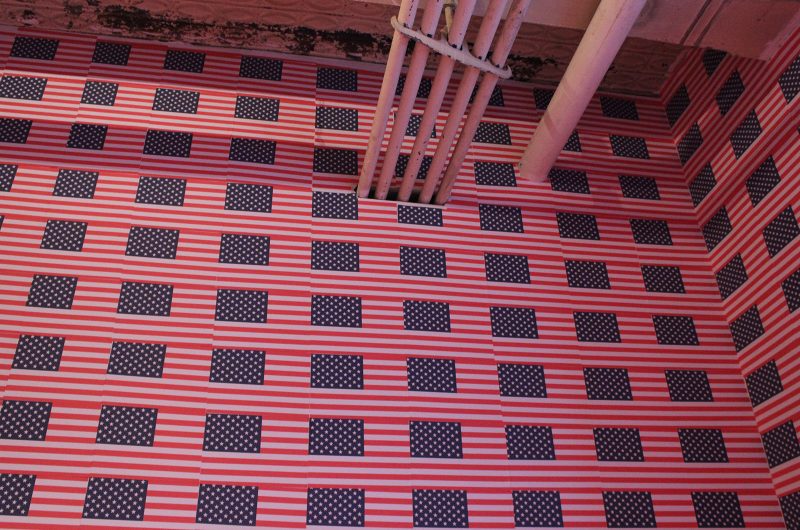 Floor-to-ceiling flags at 'So Help Me God.'