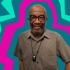 A Black man wearing a short sleeve shirt and glasses looks at you. Bold, graphic lines of pink and green radiate around him.