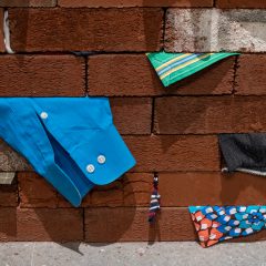 Close up of a wall of bricks with bits of clothes stuffed in between each brick.