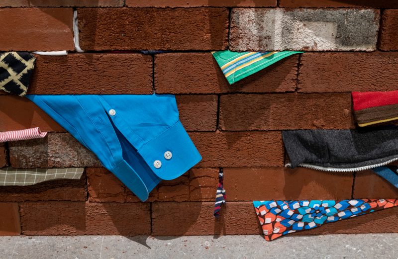 Close up of a wall of bricks with bits of clothes stuffed in between each brick.