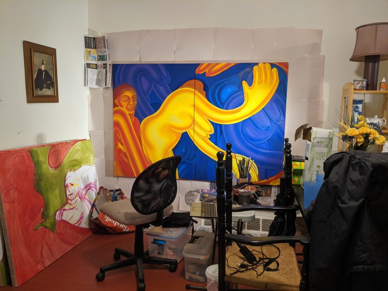 Artist studio with a rolling chair, various supplies, and two large in-progress paintings of figures.