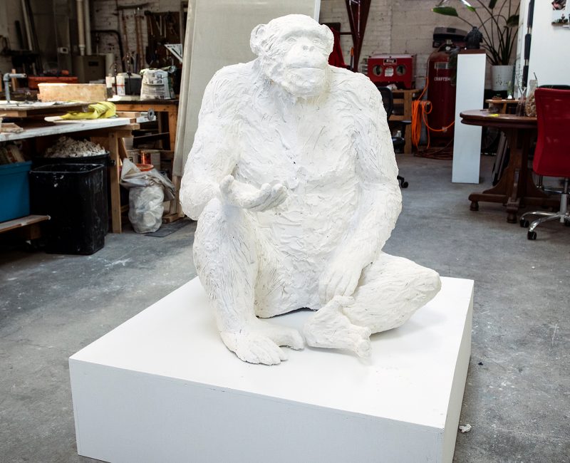 Plaster sculpture of a chimpanzee in a seated position.