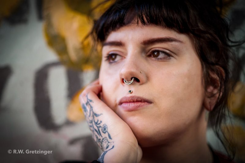 Close-up of a woman with her hand underneath her chin looking into the distance.