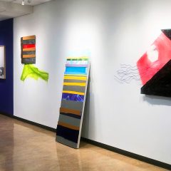 Installation view of "Interconnected" with large abstract works of art on the wall, primarily paintings.
