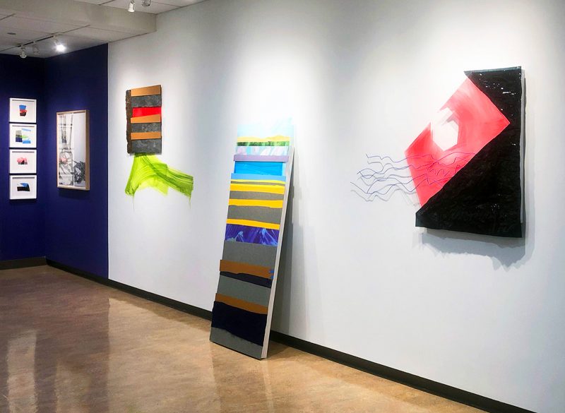 Installation view of "Interconnected" with large abstract works of art on the wall, primarily paintings. 