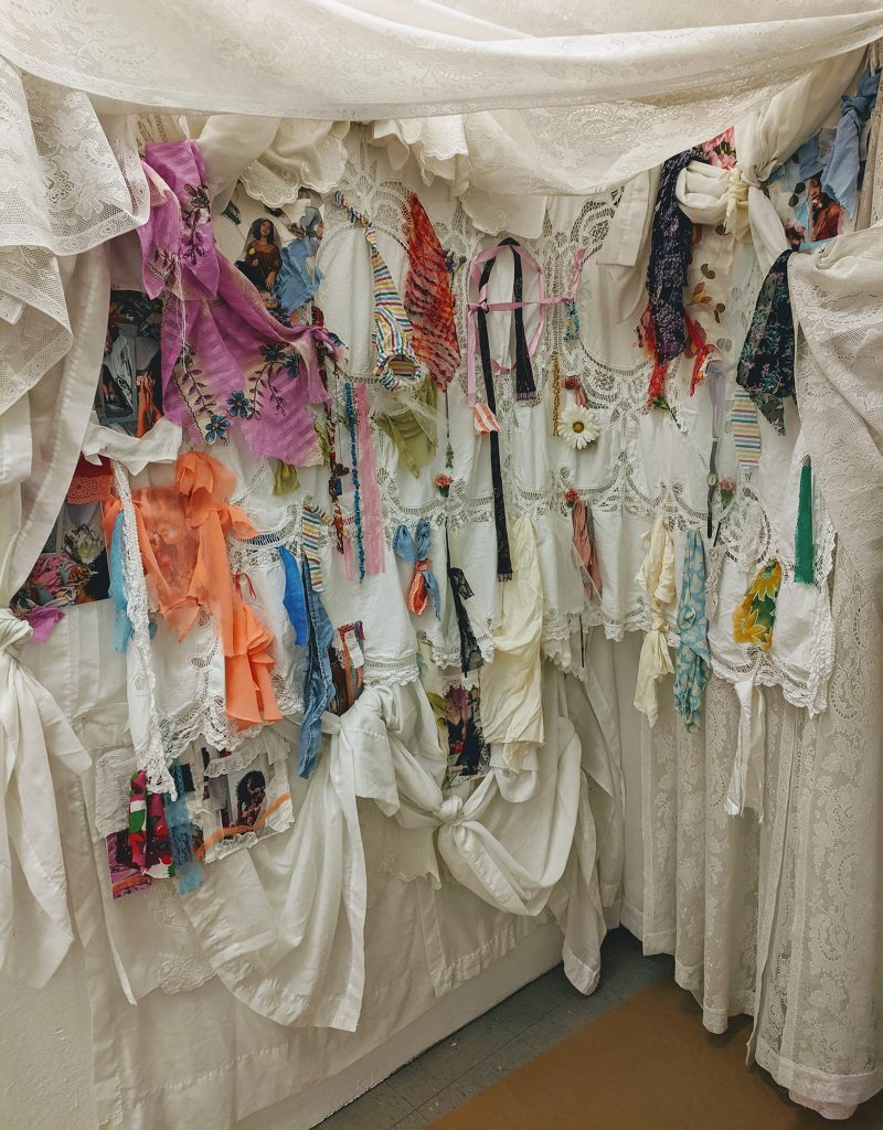 Fabric installation containing lace, striped fabric, a flower, and various patterned swatches.