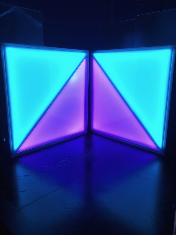 Glowing light sculpture featuring blue and pink squares, split on a diagonal creating two triangles of color, one pink and one blue. Courtesy Nina Valdera.