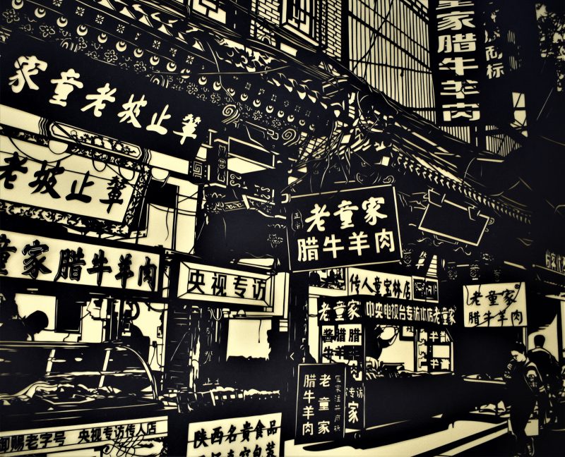 Black cut paper depicting a street full of various restaurants and stores