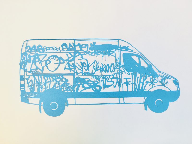 Blue cut paper depicting a white work van covered with graffiti
