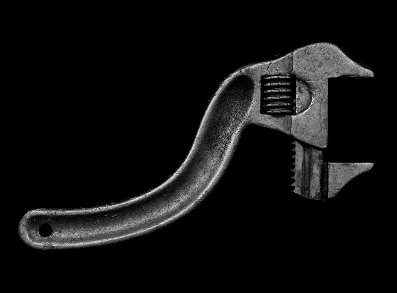 Above view of a black and white adjustable wrench on a black background