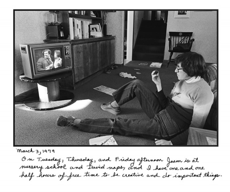 Young adult Judy Gelles sitting on the floor watching TV on a small black and white TV in a living room.