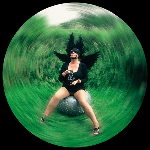 Natalia in a black costume sitting on an exercise bouncy ball. Photo is circular with a radial blur effect.