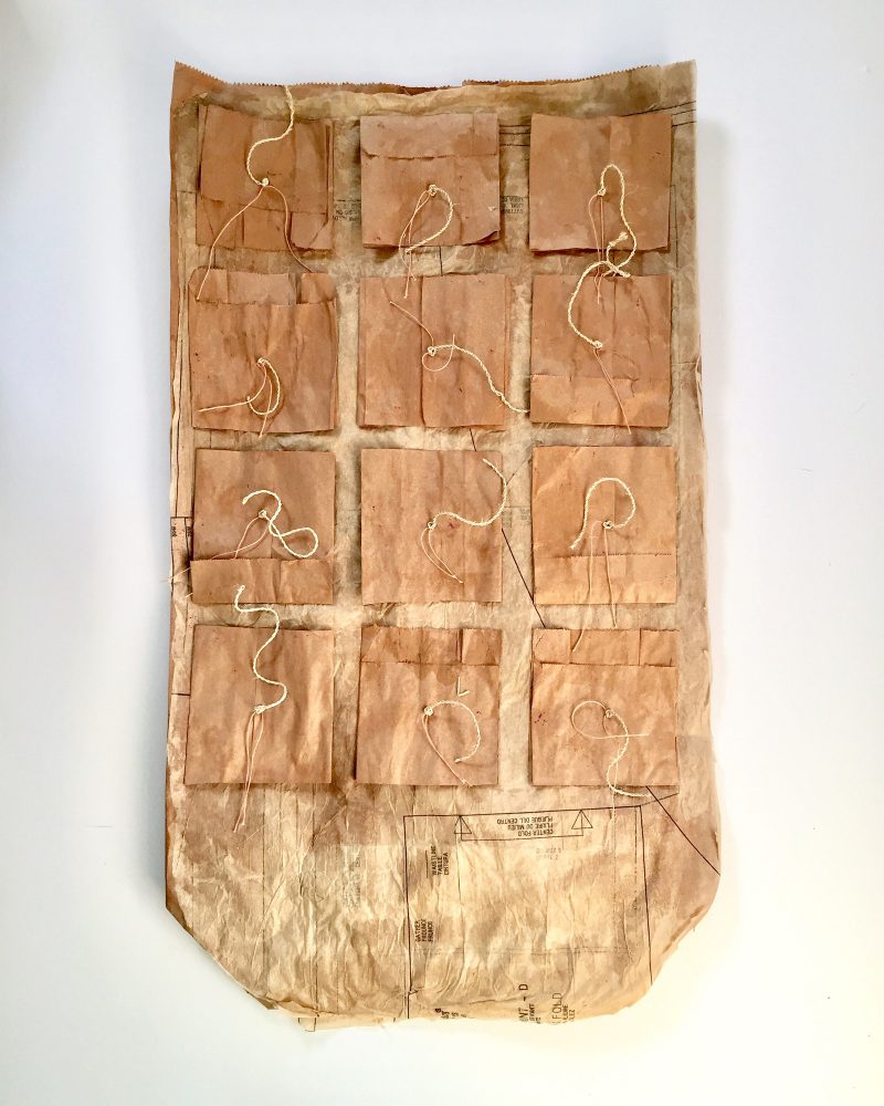 Brown paper squares collaged onto a large brown paper rectangle with string 