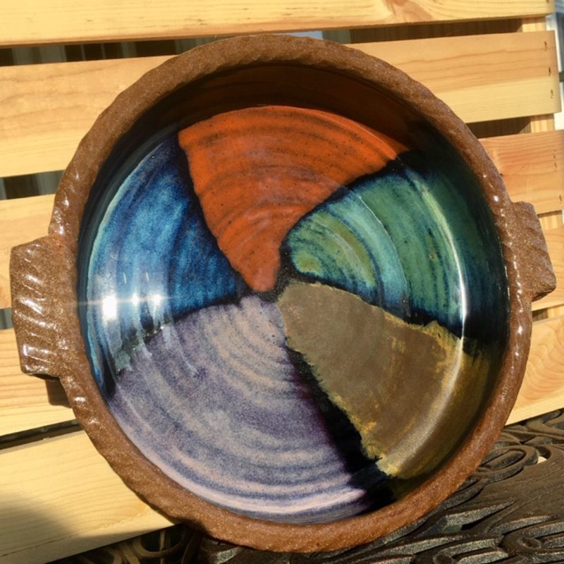 Decorative ceramic bowl with a spiral color design inside.