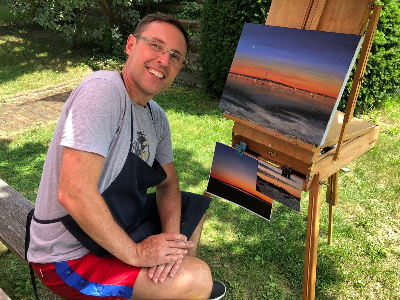 Joao painting on an easel outdoors.