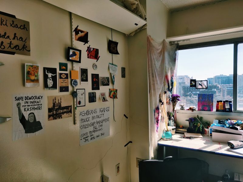 Studio with large windows with a desk propped up against the wall and various photographs and notes pinned to the wall.