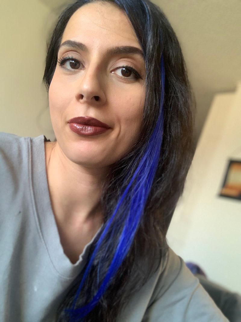 Self-photo of Arianna wearing a blue hair extension.