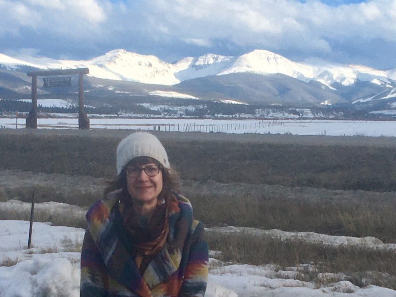 Phyllis Anderson standing in front of a snowy mountain.