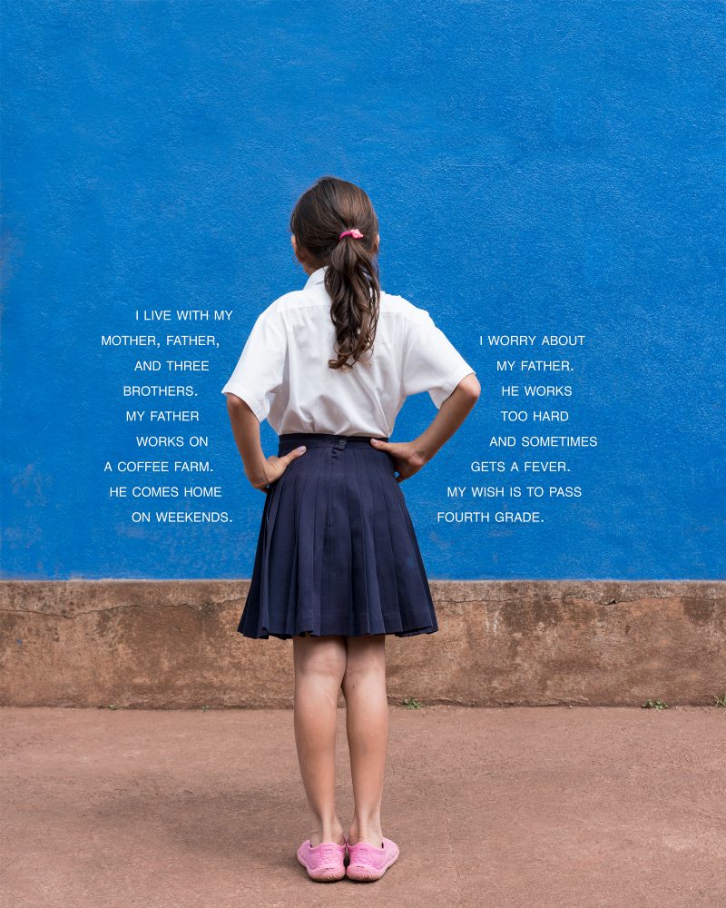 Young girl starting at a blue wall in a school uniform with text around her.