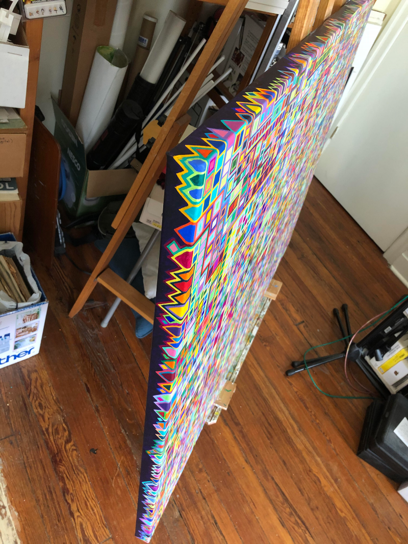 Photo of an abstract geometric painting leaning against an easel displaying the edges of the painting painted with a design
