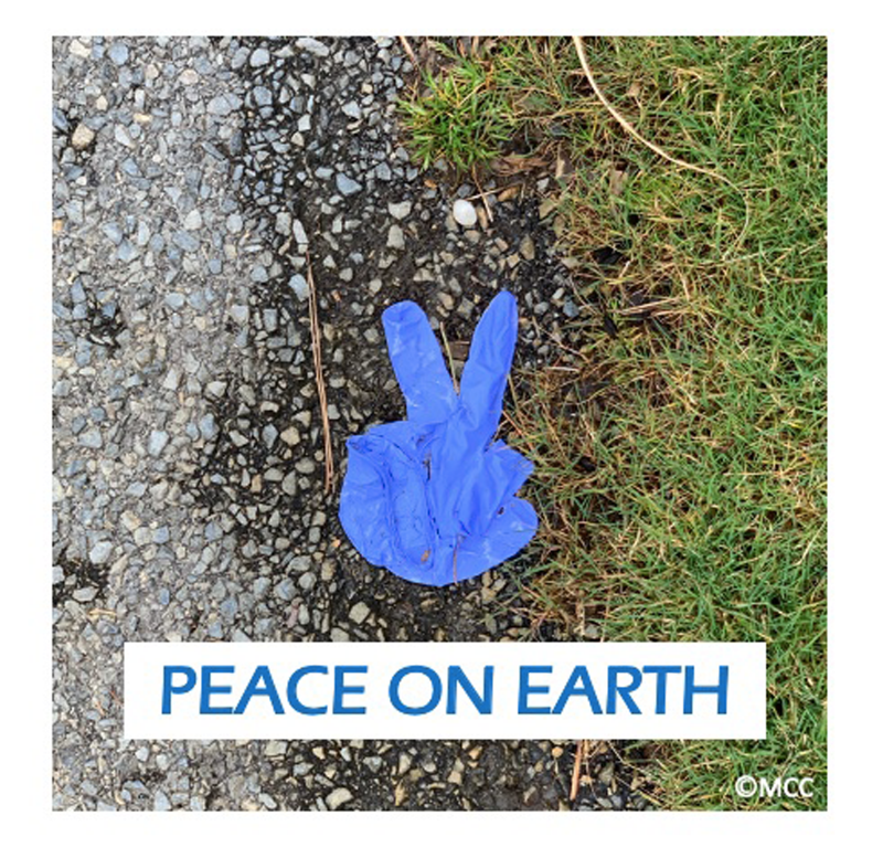 Blue latex glove manipulated into a peace sign, photographed on grass and dirt with "PEACE ON EARTCH" superimposed on the bottom of the photo.