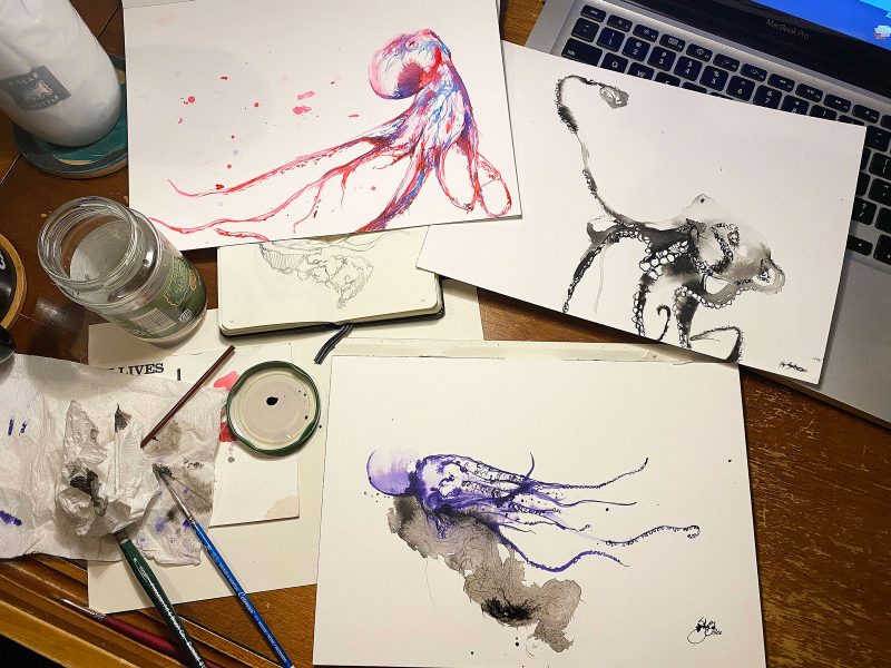 Color ink drawings of octopi spread on a desk.