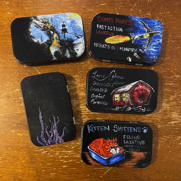 Five painted altoid cases on a desk.