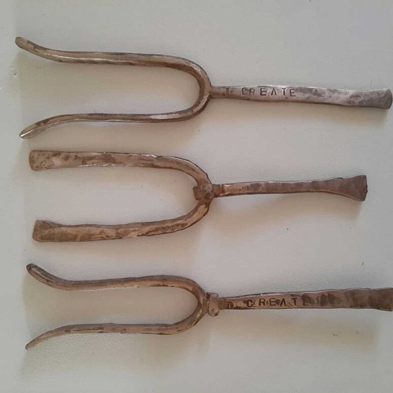 Three bronze tuning forks with "CREATE" written on the handle