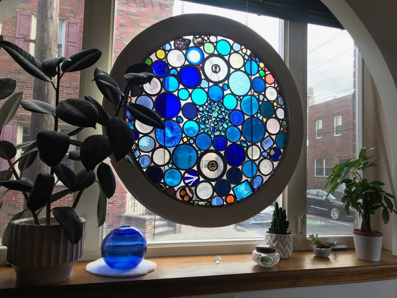 Stained glass window hanging in the window of a philadelphia home.