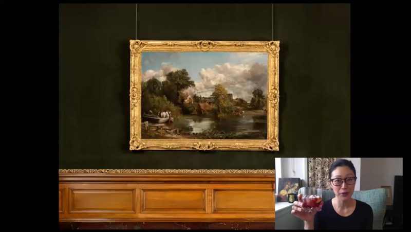 Video chat with a woman drinking a glass of wine with a large landscape painting behind her.
