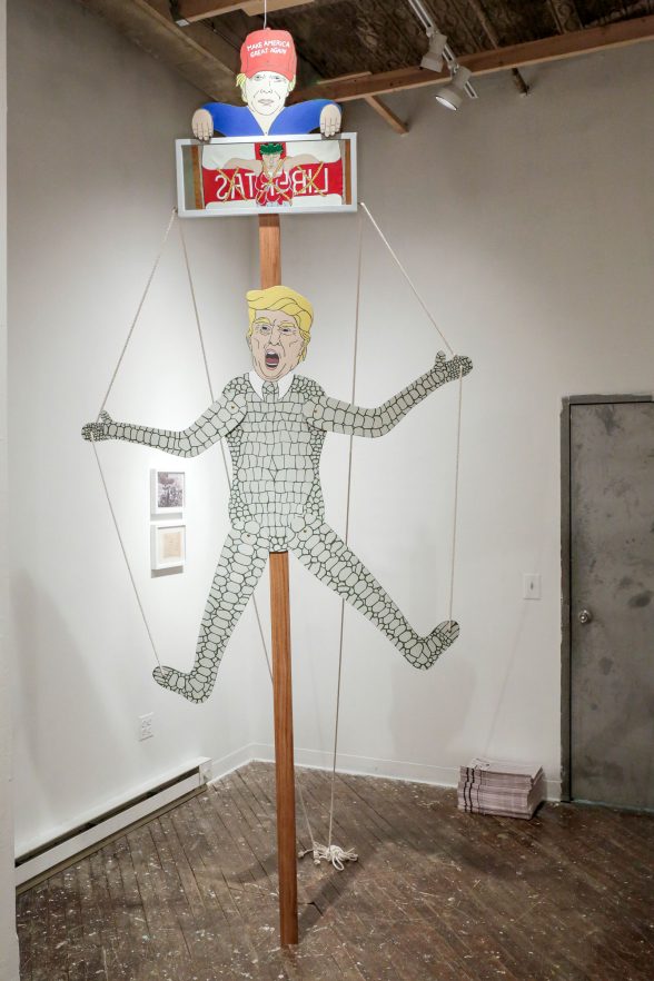 Sculpture of donald trump on a pulley device like a puppet.