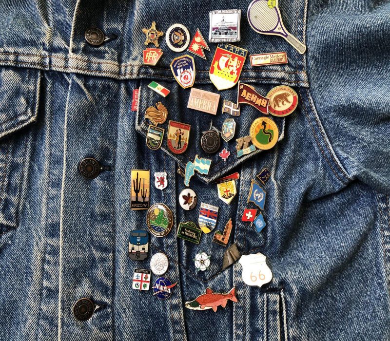 A large collection of pins on a jean jacket.