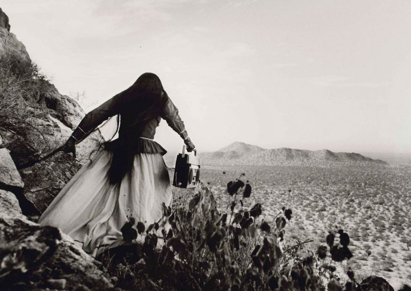 Woman carrying a boombox into a field