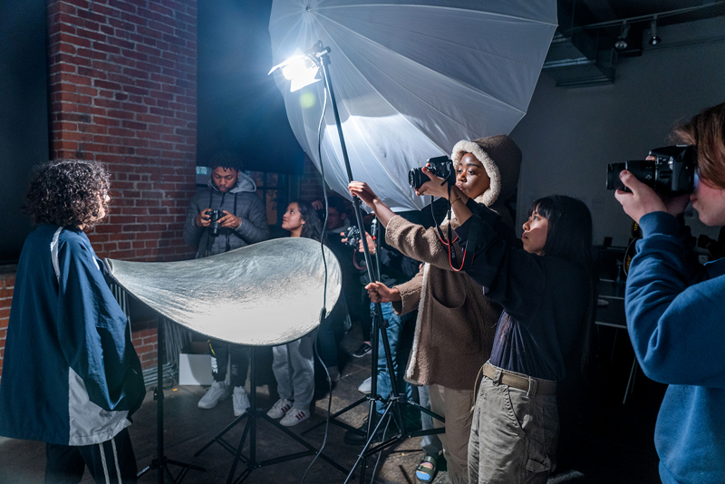 Teens staging photo lighting equipment in a class.