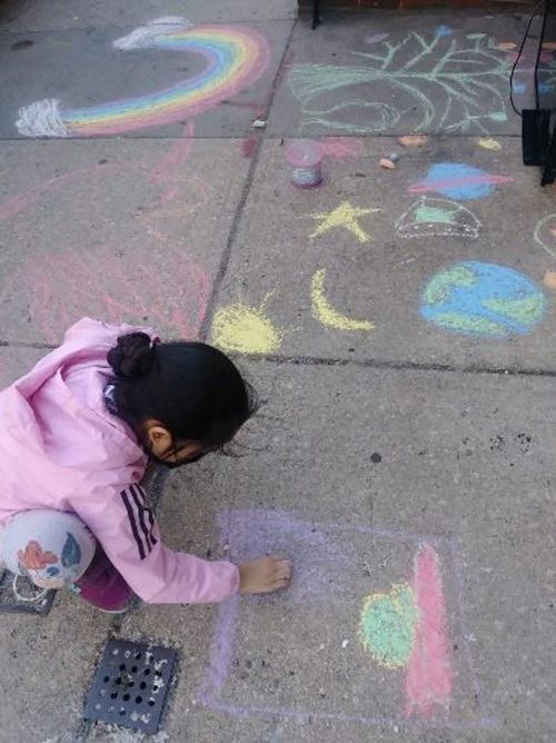 Child drawing with chalk on the sidewalk