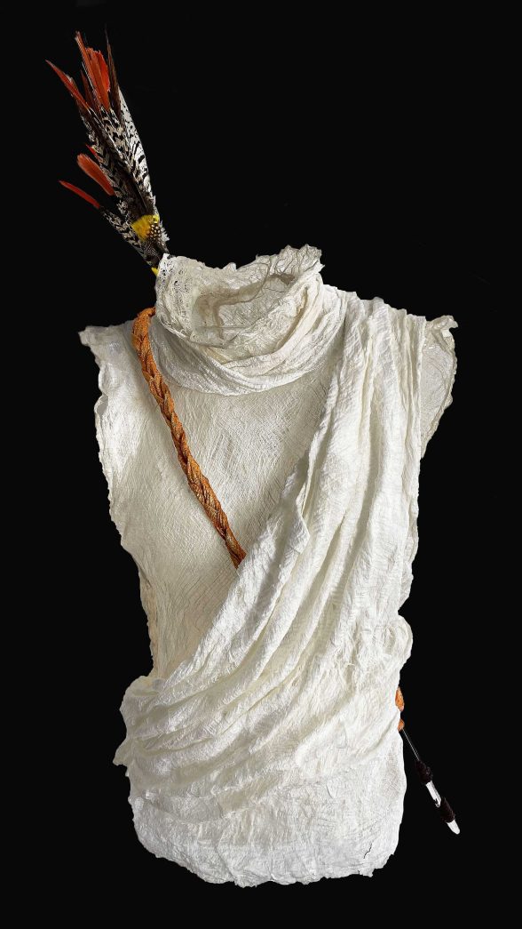 Sculpture of a white garment in the shape of a female torso with arrows hanging around the the back.