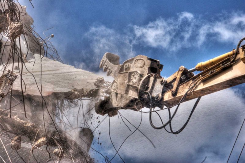 A construction machine mid-demolition of a building