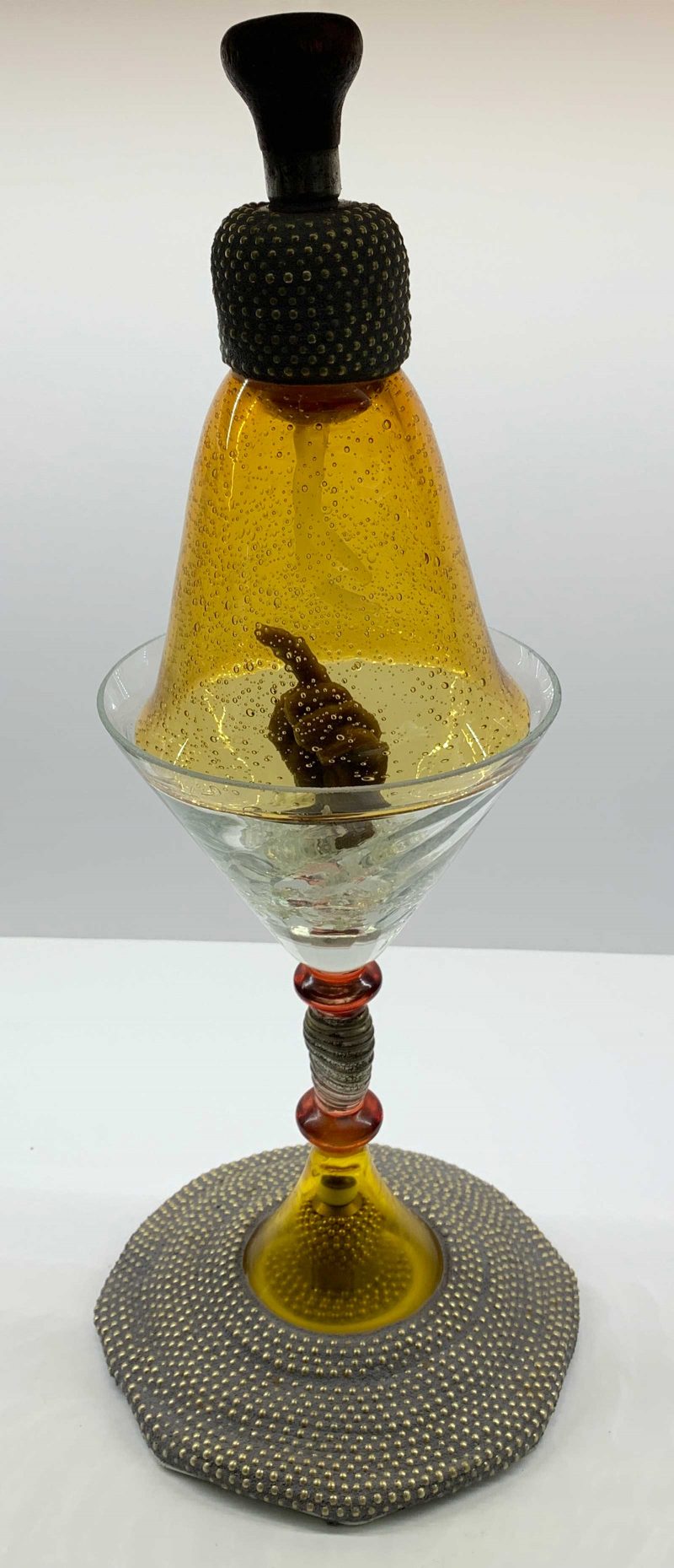 marini glass with a hand with a pointed figure inside covered by a glass dome.