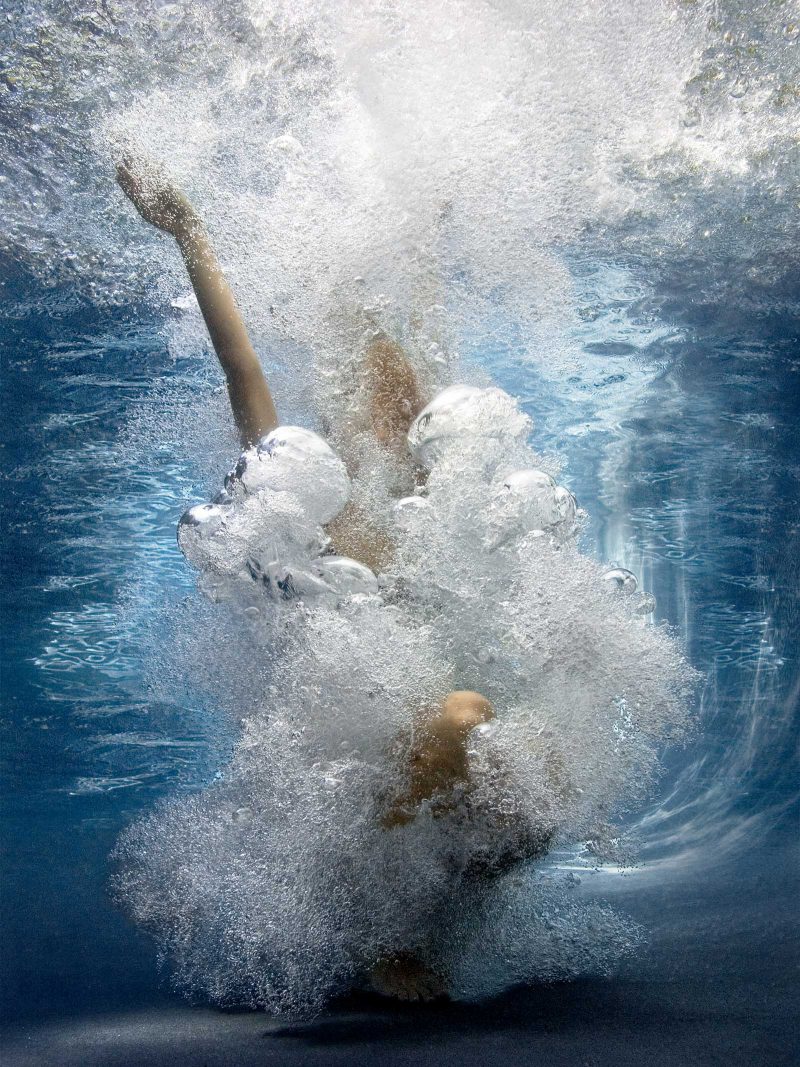 A woman falling into water surrounded by bubbles that obscure her body.