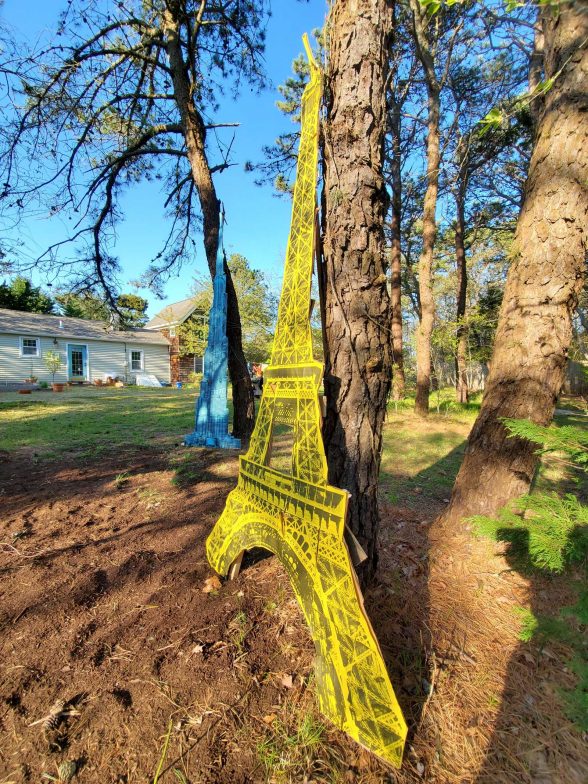 Printed downscale model of the eiffel tower installed amongst trees. 