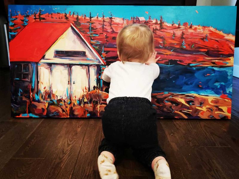 Small child reaching out and touching the landscape painting.