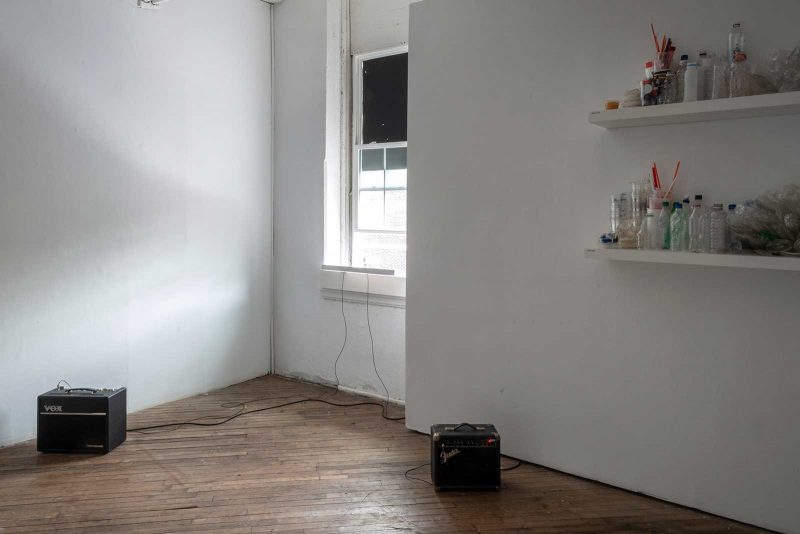 Amplifiers attached to a window pane hanging outside of an open window in a gallery.